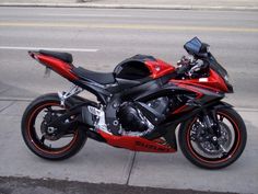 a red and black motorcycle parked on the side of the road next to a curb