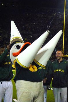 the mascot is dressed in green and white with orange beaks on it's head