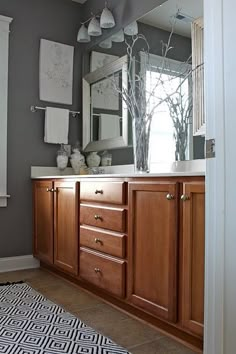 a bathroom with wooden cabinets and gray walls