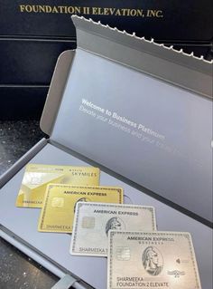 three american express credit cards sitting in a metal case on top of a black counter