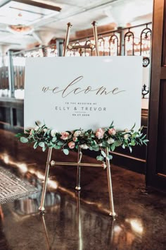 a welcome sign with flowers and greenery on it