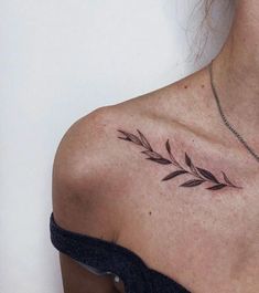 a woman with a tattoo on her shoulder has a leaf design on the back of her shoulder