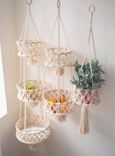 three macrame baskets hanging on the wall with succulents and fruit in them