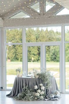 the table is set up in front of large windows with string lights hanging from them