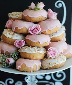 a tower of donuts with pink frosting and flowers on top, sitting on a cake plate