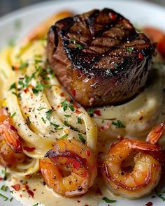 a white plate topped with pasta and meat covered in sauce, garnished with shrimp