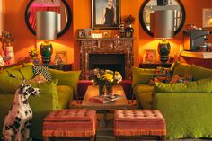 a living room with orange walls and green couches in front of a fire place