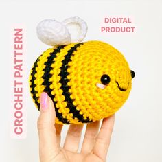 a hand holding a small crocheted yellow and black ball with a white cloud on top