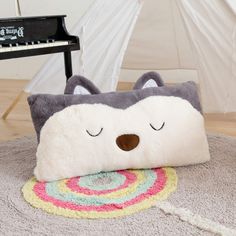 a pillow with a cat face on it sitting on the floor next to a piano