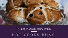 there are many bread buns in the glass bowl on the table with words that read, irish home recipes hot cross buns