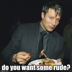 a man in a suit and tie holding a plate with food on it while looking at the camera