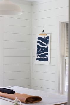 a white room with wood paneling and a painting hanging on the wall next to a bed