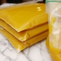 four bags of yellow food sitting on top of a counter next to a plastic cup