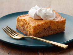 a piece of pie on a blue plate with a gold fork and whipped cream topping