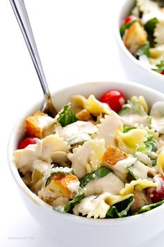 two bowls filled with pasta and vegetables on top of a white table next to each other