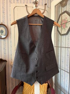 This classic vest is made from a wool blend in a very small charcoal grey and black houndstooth check. It has the original buttons in the front and four front pockets, and is fully lined with dark grey silky lining. The back matches the lining. The measurements, taken with the vest lying flat, are: shoulder to shoulder, 14 inches; armpit to armpit, 22 inches; length, 26 inches in front and 23 inches in back; bottom edge, 22 inches. In very good condition. Wool Business Vest For Fall, Wool Vest For Business In Fall, Business Wool Sleeveless Vest, Classic Gray Vest For Work, Classic Tweed Vest For Work, Classic Business Vest For Winter, Gray Fitted Vest For Business, Fitted Gray Vest For Business, Classic Gray Formal Vest