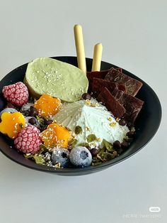 a black plate topped with fruit and ice cream