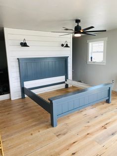 a large bed sitting on top of a hard wood floor next to a ceiling fan