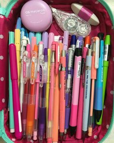 a pink case filled with lots of different colored pens and markers on top of it