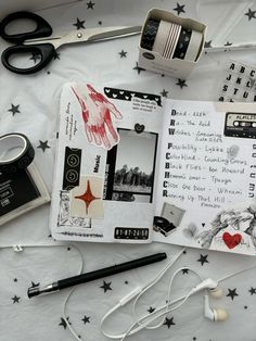 an open book with some scissors and other items on top of the table next to it