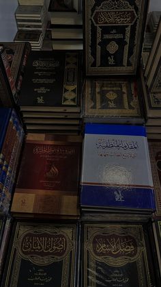 many books are stacked on top of each other in different colors and sizes, all with arabic writing