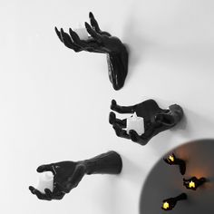 three pieces of art that look like hands and legs on a wall with candles in them