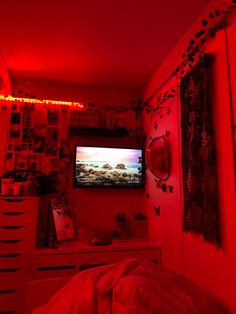 a bedroom with red lights and pictures on the wall, tv in the corner next to bed