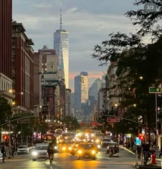 a city street filled with lots of traffic and tall buildings in the background at dusk