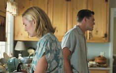 two people are standing in the kitchen looking at something on the counter top that they are holding