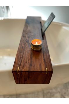 a candle sitting on top of a wooden box in front of a bathtub with a mirror