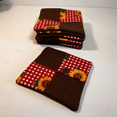 three pieces of cloth with sunflowers on them sitting on a white table top