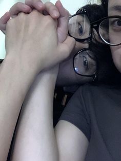 two people wearing glasses are posing for the camera with their hands on each other's shoulders