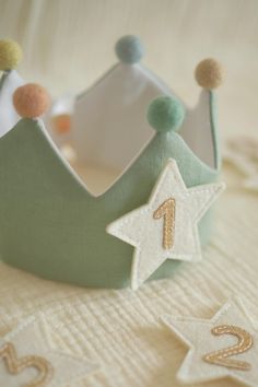 a green crown sitting on top of a bed next to two white star shaped stars