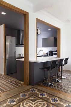 an open kitchen and living room area with bar stools on the floor in front of it