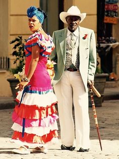 a man and woman dressed in colorful clothing standing next to each other on the street