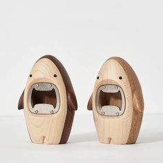 two wooden toys shaped like animals on a white surface, one has its mouth open and the other is closed