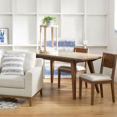 a living room filled with furniture and a wooden table in front of a white bookcase