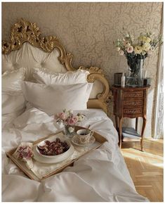 a tray with food on it sitting on top of a bed next to flowers and vases