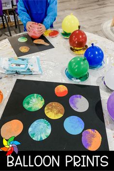 a table with balloons and other items on it, including paper plates that look like planets