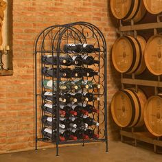 a wine rack filled with lots of bottles in front of a wall full of barrels