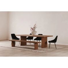 a wooden table with black chairs and a white vase on top of it in front of a wall