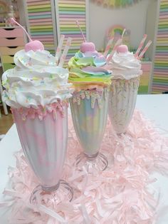 three decorated cupcakes sitting on top of pink shredded paper