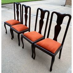 three chairs with orange cushions sitting on the sidewalk