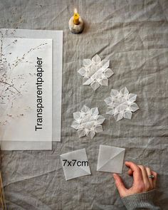 someone is making origami snowflakes out of paper on a sheet of fabric