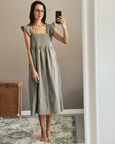 a woman standing in front of a mirror taking a selfie with her cell phone