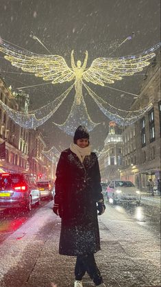 a woman is walking down the street in the snow with an angel decoration above her head