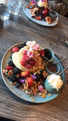 pancakes with fruit and whipped cream are on a blue plate at a restaurant dining table