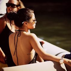 a woman sitting on top of a boat next to another person in a black bathing suit