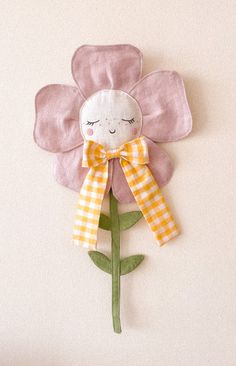 a pink flower with a yellow bow hanging on the wall