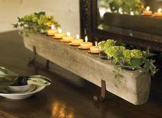 a wooden bench with candles and flowers on it next to a bowl full of lettuce